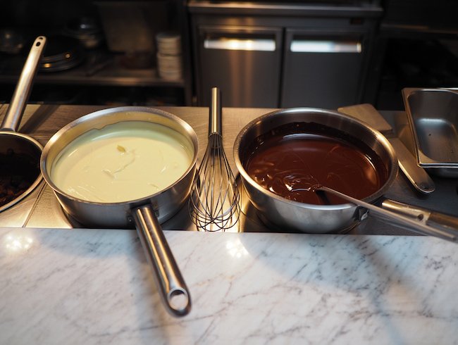 Deux casseroles contenant du chocolat blanc et du chocolat noir en train de fondre.