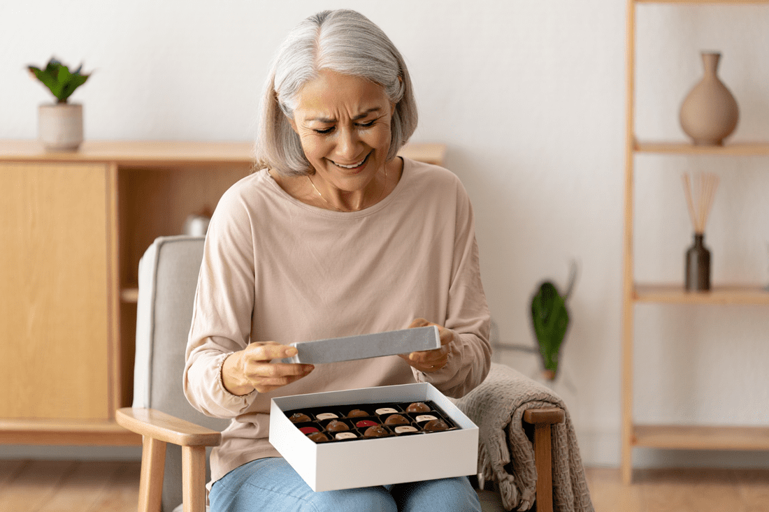 Photo d’une femme qui ouvre une boîte de chocolats avec le sourire aux lèvres